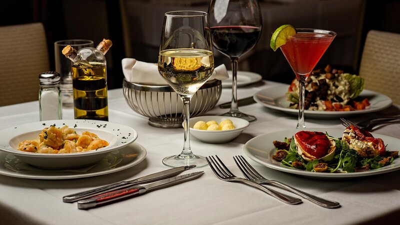 Multiple plated entrees and salads with several cocktails